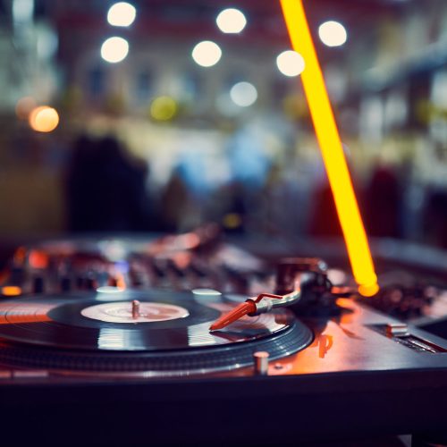 turntable, vinyl record at night club. blured background.